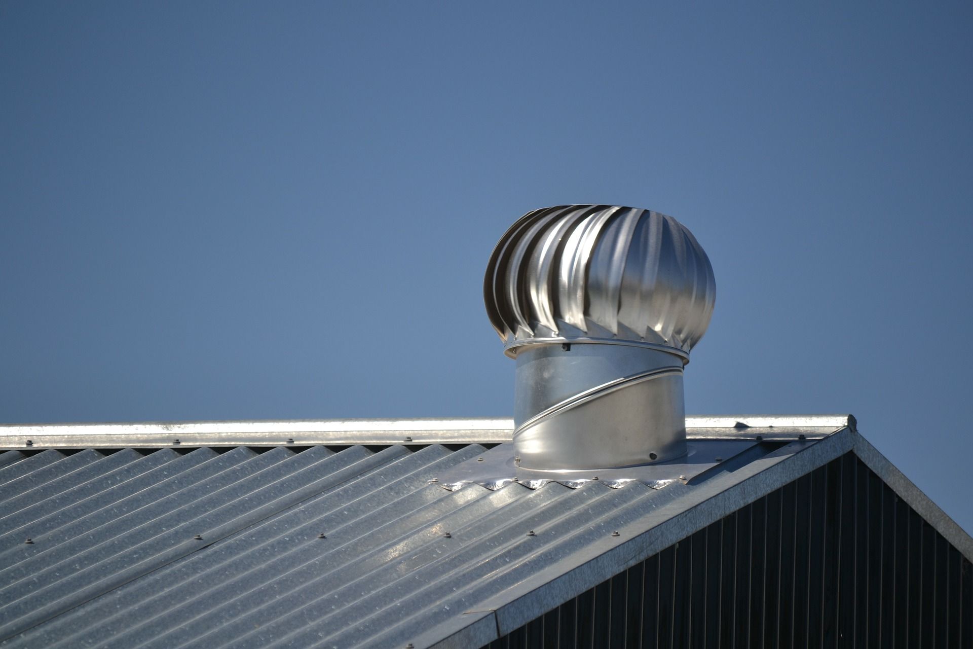 Image of a shiny turbine roof vent on a shiny metal roof.