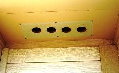 Image of 4 round holes drilled behind the soffit vent, not providing much airflow into the attic.